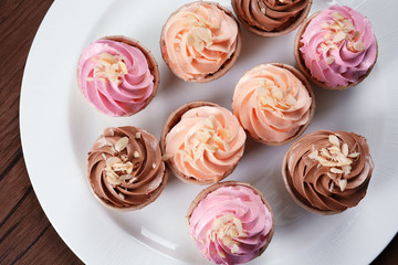 Delicious creamy cakes in white plate, top view