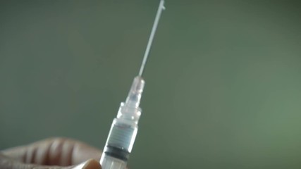 Hand using hypodermic syringe and spraying out liquid in slow motion - Powered by Adobe