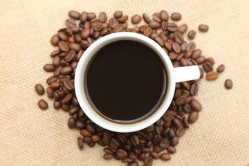 cup of coffee with roasted coffee on burlap sack