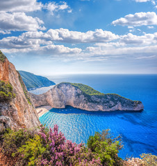 Navagio beach with shipwreck and flowers against sunset on Zakynthos island in Greece - obrazy, fototapety, plakaty