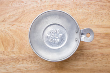 measuring one half cup on wooden background, top view
