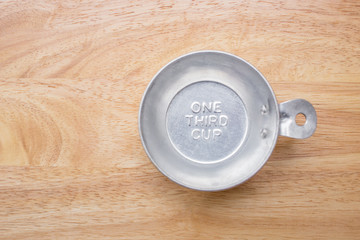 measuring one third cup on wooden background, top view