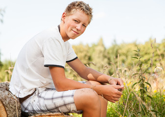Handsome friendly young boy sitting outdoors