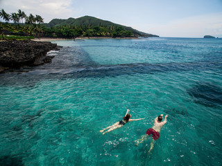 Romantic couple swimming in blue water of Indian ocean holding hands while honeymoon vacation