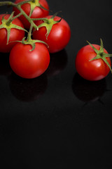 Frische reife Tomaten auf schwarzem Stein, Spiegelungen