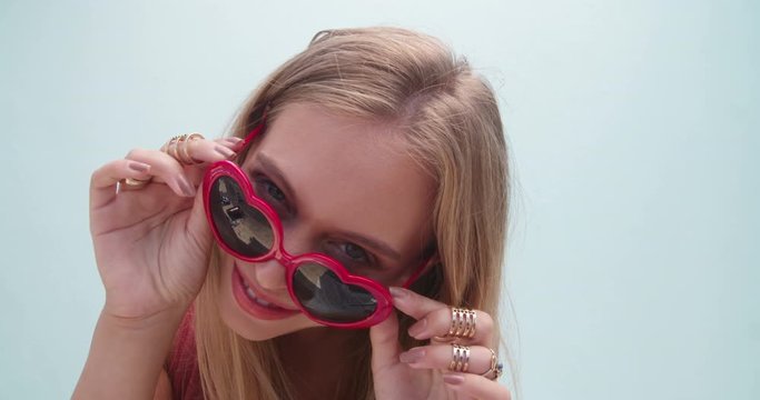 Beautiful blonde girl with red sunglasses and orange lips