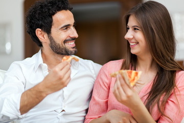 Couple eating pizza on the sofa
