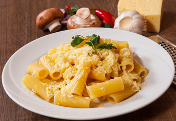 rigatoni pasta with cheese in a plate on wooden table