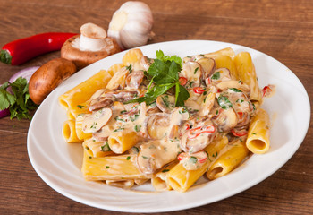 rigatoni pasta with mushroom sauce in a plate on wooden table