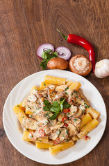 rigatoni pasta with mushroom sauce in a plate on wooden table