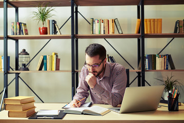 Attractive businessman reading book at home office