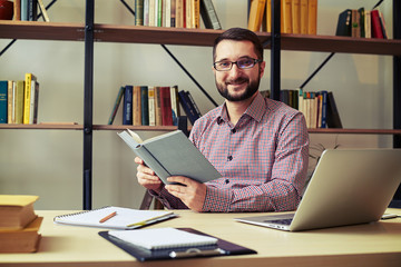 Man with the glasses reading book and making notes