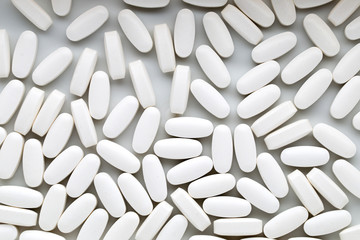 White pills on the white background.