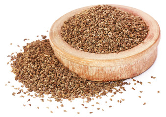 Ajwain seeds in a wooden bowl over white background