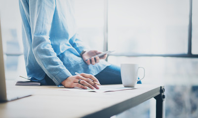 Photo young business woman working with new startup project in modern coworking office. Sitting wood table, holding smartphone hands, cup of coffee. Horizontal, blurred