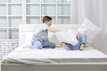 Young children playing on the bed. Pillow fight