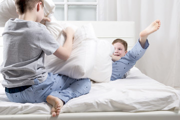 Young children playing on the bed. Pillow fight