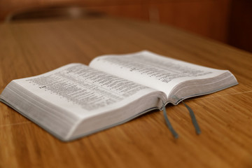 Fototapeta premium Bible on table. Holy Bible book on a background. Bible on old wood table. Beautiful dark background. Religious concept. The Holy Bible on a wooden table. Breakfast with the Holy Scriptures.