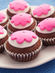 Glazed cupcakes with white and purple glazing on white plate. Vertical shot