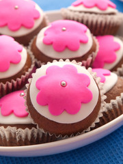 Glazed cupcakes with white and purple glazing on white plate. Close up, vertical shot