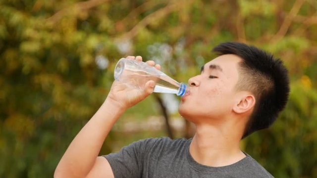 Close-up of a young man drinking water from a bottle outside