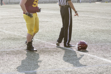American football player, referee and helmet on the field 