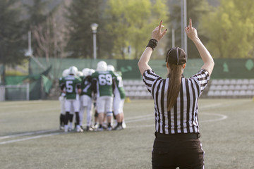 Female American football referee and blurred players in the background 