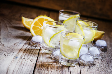Cold Russian vodka with lemon and ice in shot glass, vintage woo - obrazy, fototapety, plakaty