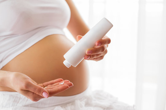 Pregnant woman using moisturizer