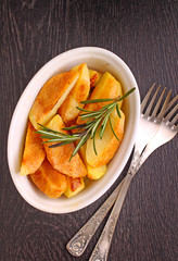 baked potatoes with spices in white bowl on a black background