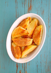baked potatoes with spices in white bowl on an old wooden background