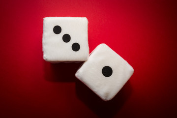 Pair of white plush dices on the red background