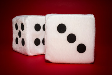 Pair of white plush dices on the red background