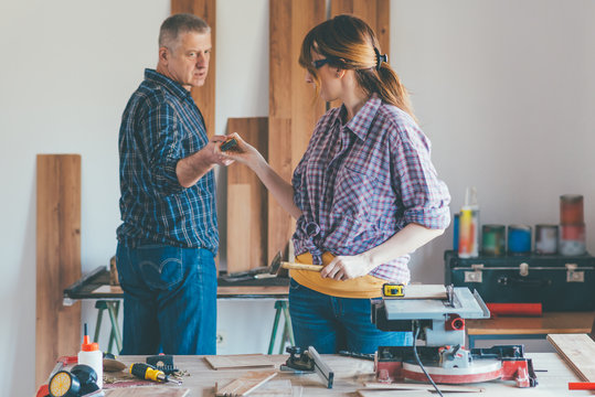 Young woman working at carpenter shop with here teacher..