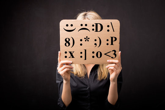 Woman holding cardboard with different emotion smileys in front of her face