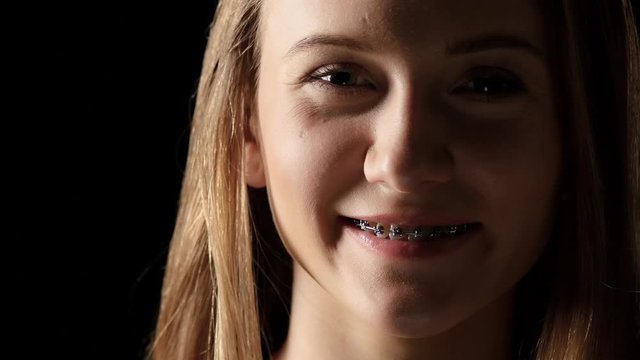 Girl in the shade with braces smiling. Black