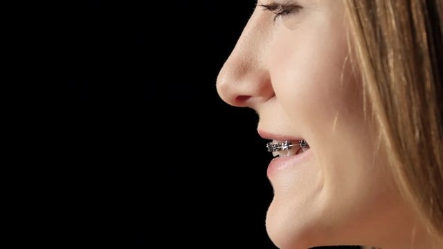 Girl in profile with braces laughs. Black