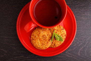red cup with tea and cookies on a black background