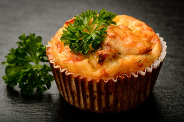 Homemade muffin with chicken and cheese on black board.