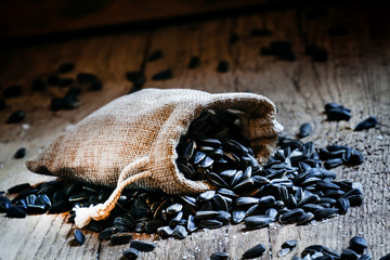 Sunflower seeds in canvas bag, vintage wooden background, select
