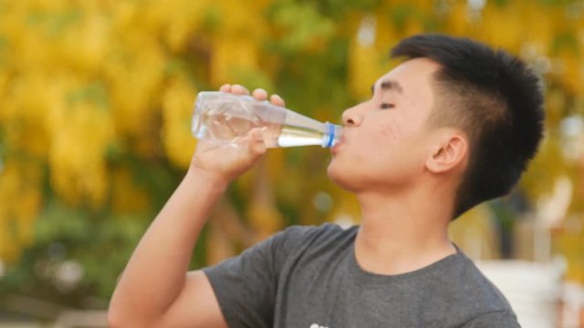 Slow Close-up of a young man drinking water from a bottle outside