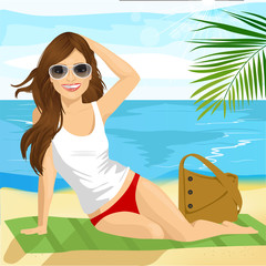 Obraz na płótnie Canvas Beautiful brunette with sunglasses sunbathing on the beach sitting on a towel