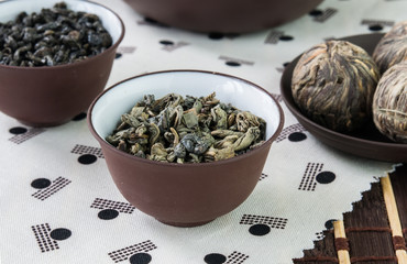 Two small bowls with green tea leaves and bundle green on Japanese pattern tablecloth