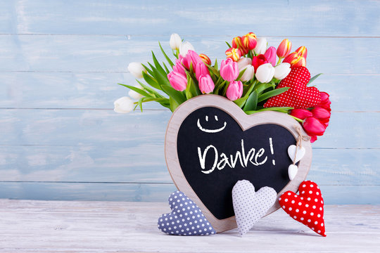 Muttertag - Bunter Blumenstrauß, Herzen und Tafel mit Aufschrift DANKE vor Holzhintergrund - Powered by Adobe