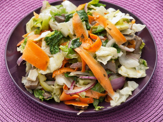 Healthy salad with lettuce, carrots and mushrooms over purple background