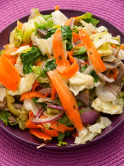 Healthy salad with lettuce, carrots and mushrooms over purple background