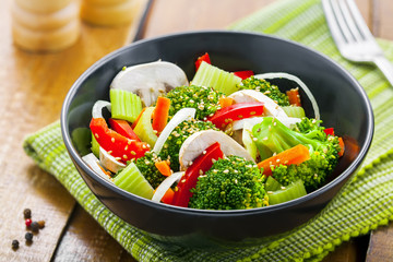 Steamed broccoli with onion, mushroom, carrot and pepper. Vegetable salad in bowl. International healthy vegetarian food.