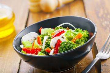 Bowl of healthy vegetarian food. Salad with broccoli, onion, mushroom, carrot and pepper.
