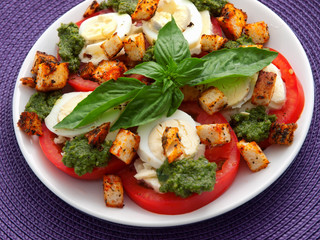 Healthy salad with tomatoes, boiled eggs, pesto and croutons. Horizontal shot