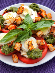 Healthy salad with tomatoes, boiled eggs, pesto and croutons. Vertical shot